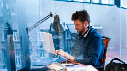 focused-male-computer-programmer-working-on-laptop-at-desk-in-office