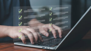 Business professional typing on laptop with virtual checklist interface.