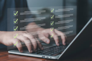 Business professional typing on laptop with virtual checklist interface.