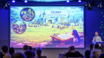 Large conference screen with fairy tale image and man with microphne presenting