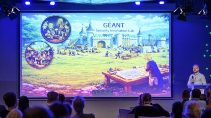 Large conference screen with fairy tale image and man with microphne presenting
