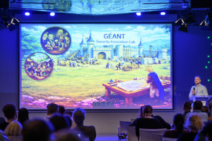 Large conference screen with fairy tale image and man with microphne presenting