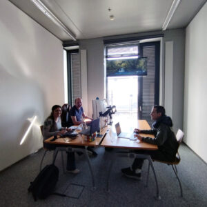 People sitting at a table with laptops and screens