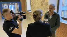 A cameraman, a woman with microphone interviewing a man