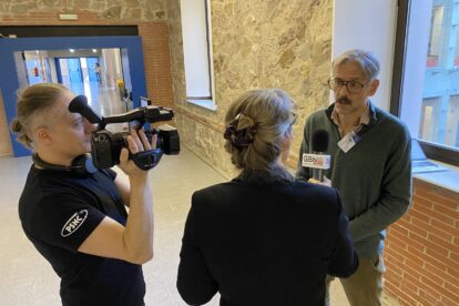 A cameraman, a woman with microphone interviewing a man