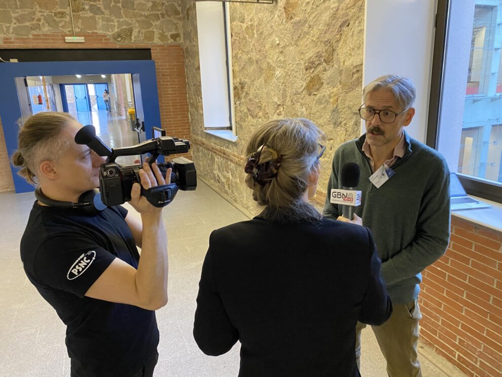A cameraman, a woman with microphone interviewing a man